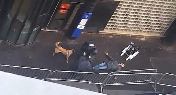 In this image taken from a validated UGC video, the body of man lies on the ground as police officers and a police dog check the body after the man was shot dead by officers at a police station in northern Paris. Pic: AP