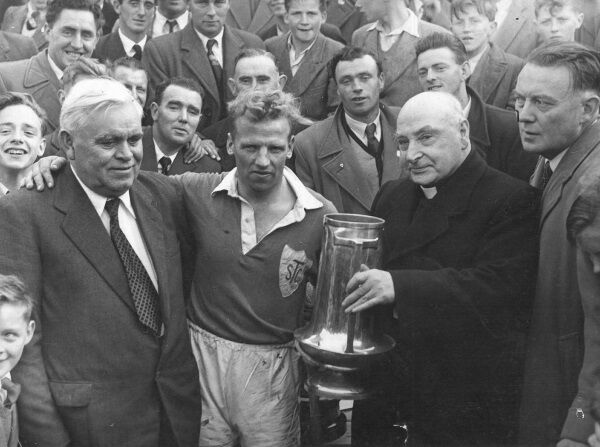 Mickey ‘The Rattler’ Byrne receives the Dan Breen Cup in the presence of Dan Breen himself. Rattler joked he was the first man who left a hand on Breen and lived to tell the tale. Picture courtesy of Seamus O’Doherty. Mickey ‘The Rattler’ Byrne receives the Dan Breen Cup in the presence of Dan Breen himself. Rattler joked he was the first man who left a hand on Breen and lived to tell the tale. Picture courtesy of Seamus O’Doherty.