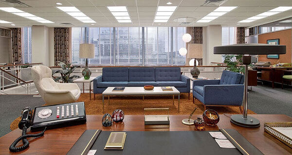 The offices of Sterling Cooper in Mad Men has the Kalff Philips table lamp in the foreground, with a Florence Knoll three-seater sofa and matching armchair.