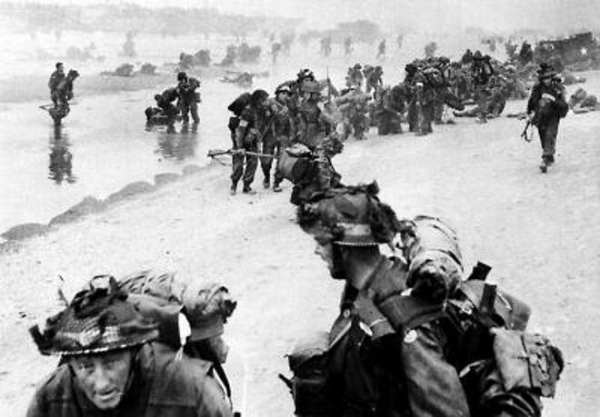 Undated picture of allied troops arriving on a Normandy beach during the D-Day landings in June 1944. As shells exploded overhead and German snipers tried to pick off the advancing commandos, Private William Millin (piper) was told to play Highland Laddie, Blue Bonnets Over the Border and Our Road to the Isles.