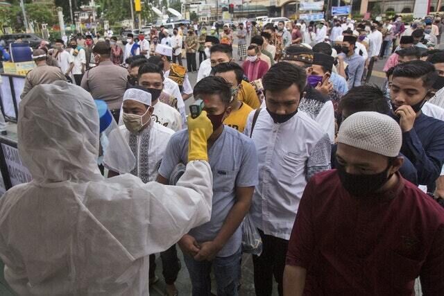 A health worker checks the temperature of worshippers prior to entering Al Mashun Grand Mosque’s compound to attend an Eid al Fitr prayer in Indonesia (Binsar Bakkara/AP) A health worker checks the temperature of worshippers prior to entering Al Mashun Grand Mosque’s compound to attend an Eid al Fitr prayer in Indonesia (Binsar Bakkara/AP)