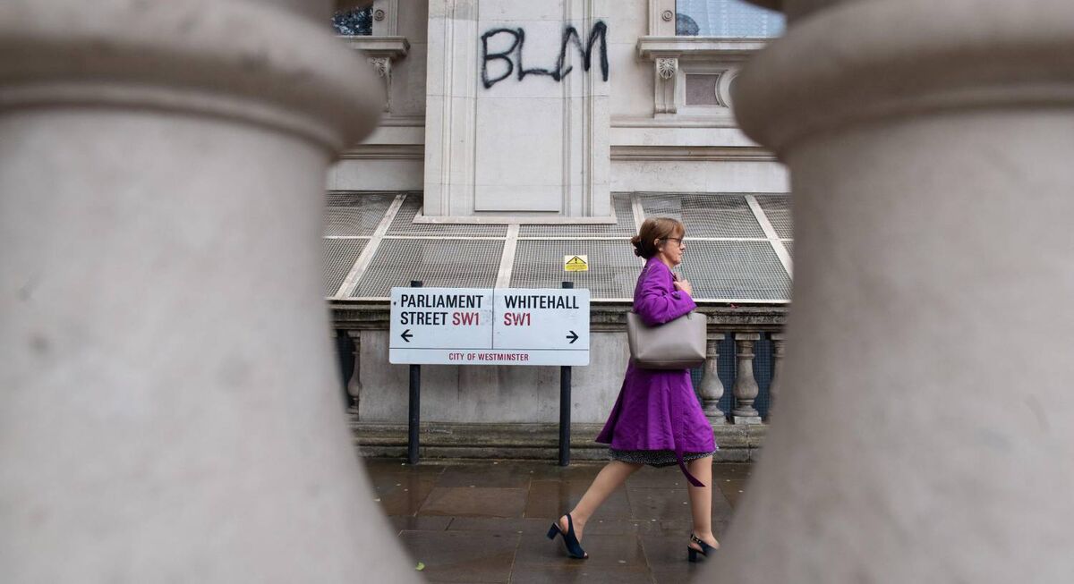 A woman passes Black Lives Matter graffiti on Whitehall, in Westminster, London, today. Pic: Dominic Lipinski/PA