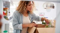 View Looking Out From Inside Of Refrigerator As Woman Unpacks Online Home Food Delivery