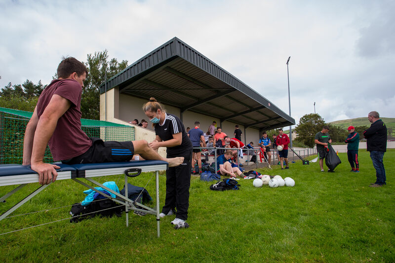 Beale player Philip Blake gets some physio before the match from Deirdre Mulvihill as teammates tog out under the stand at Valentia Young Islanders pitch in Chapeltown. Picture Alan Landers. Beale player Philip Blake gets some physio before the match from Deirdre Mulvihill as teammates tog out under the stand at Valentia Young Islanders pitch in Chapeltown. Picture Alan Landers.