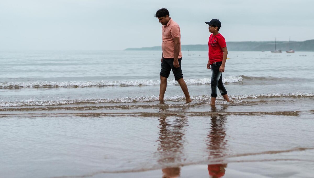 Ravi Saini and his father Nathu Ram, walking in the sea during a visit to Scarborough lifeboat station to thank them. Photo: Erik Woolcott/PA Ravi Saini and his father Nathu Ram, walking in the sea during a visit to Scarborough lifeboat station to thank them. Photo: Erik Woolcott/PA