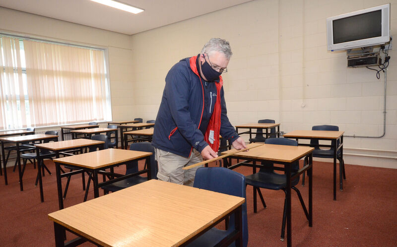 Teacher James Mancell measuring distances between chairs in one of the classrooms at Pobalscoil na Tríonóide in Youghal. Picture: Howard Crowdy