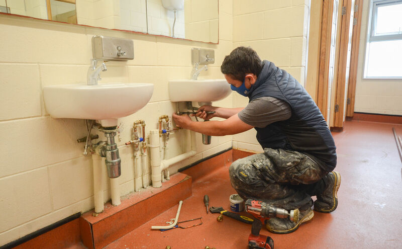 Plumber Cian Roche finishing installing new taps in the bathrooms ready for the new term in Pobalscoil na Tríonóide in Youghal next week . Picture: Howard Crowdy
