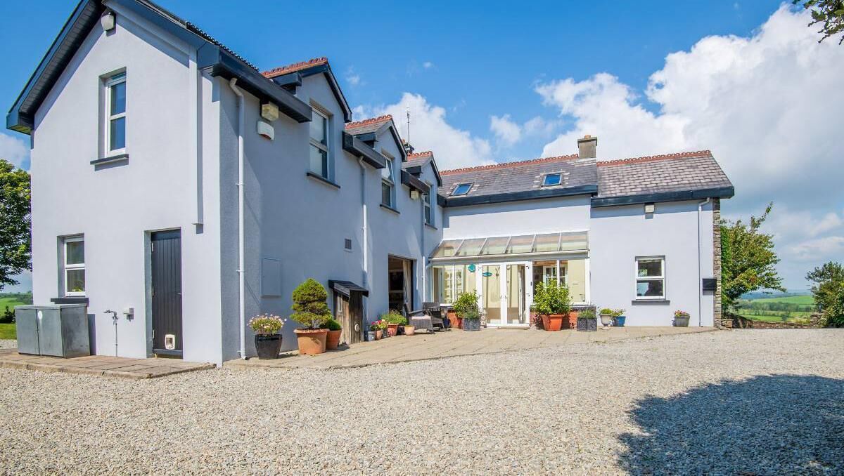 L-shaped home has sheltered glazed porch/sun-room entrance