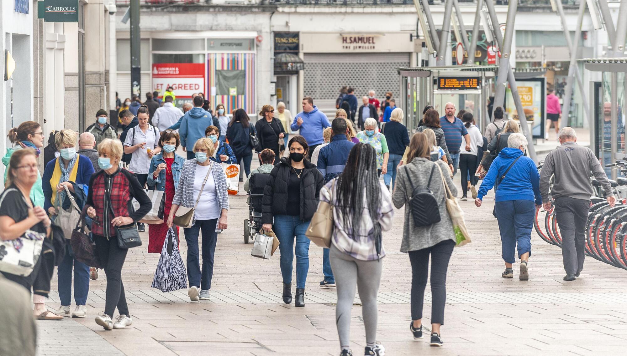 People walking along Patrick Street in Cork city in September - some with face masks and some without.