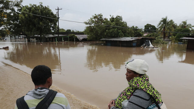 People stand by a flooded street near a river that overflowed its banks after the passing of Iota in La Lima, Honduras (Delmer Martinez/AP)