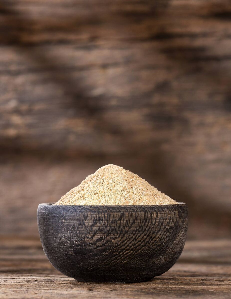 Organic maca root powder in wooden bowl - Lepidium meyenii