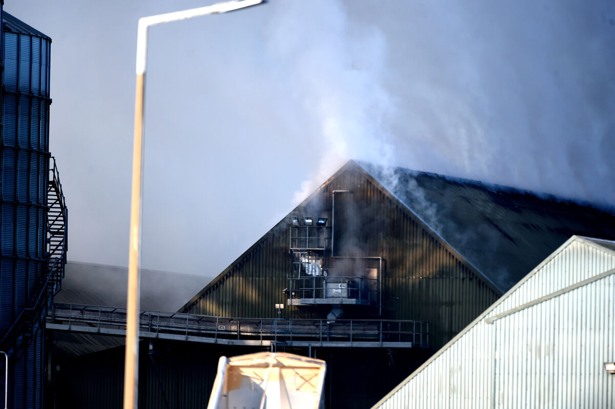 Smoke rises from the roof of a warehouse following a fire at the R&amp;H Hall grain store.