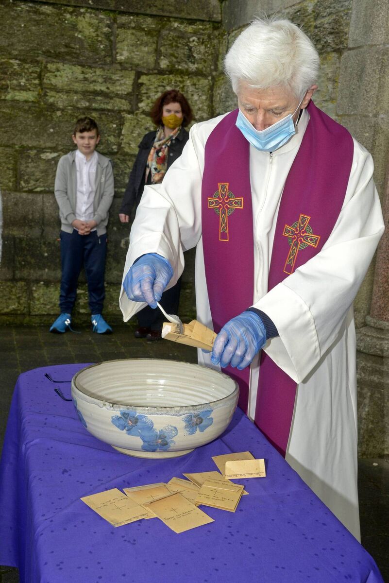 Monsignor Aidan O'Driscoll filling his envelopes for Ash Wednesday with Orla and Adhran Scully. Picture: Denis Boyle