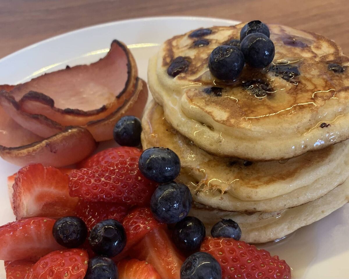 Pancakes in maple syrup, with berries and crispy rashers on the side