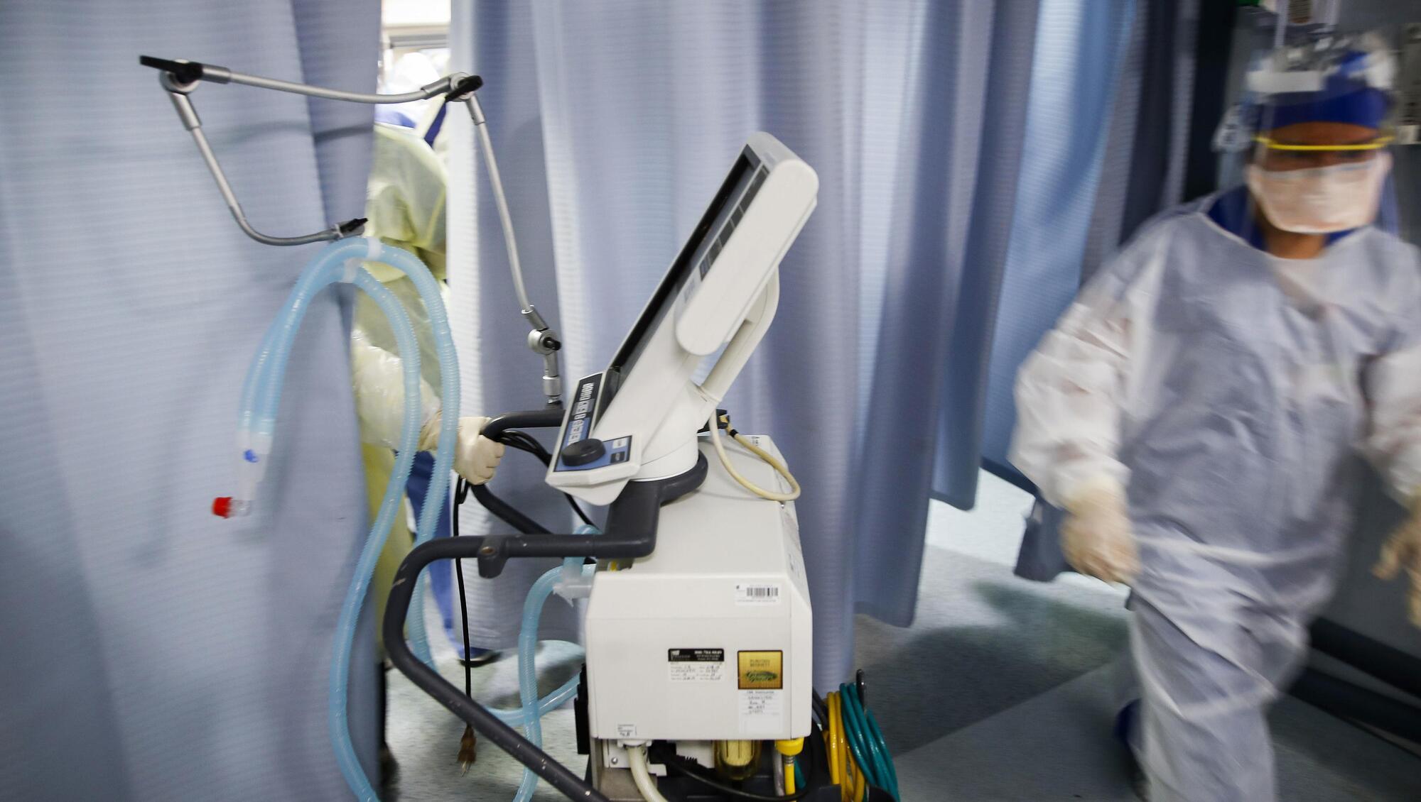 A nurse pulls a ventilator into an exam room. Picture: AP Photo/John Minchillo