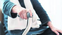 Seated senior woman supporting herself with walking stick