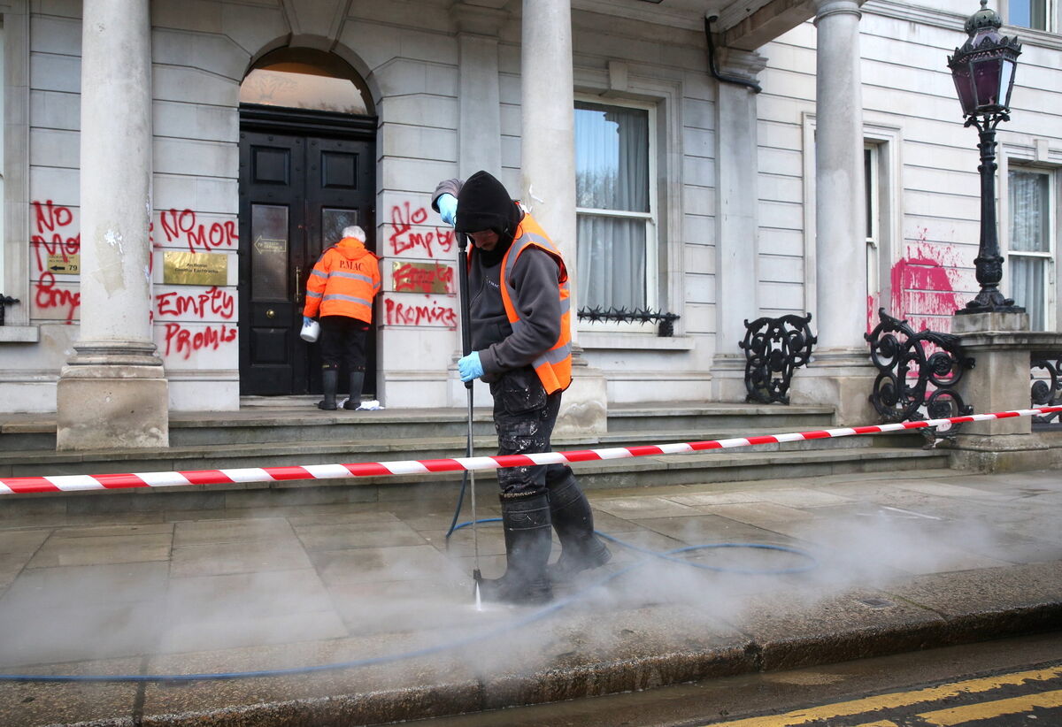 The red paint is thrown from a bucket onto one side of the façade, before being thrown from a separate bucket onto the other side.