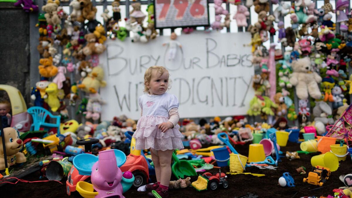  18-month-old Sophia Dilleen plays in an impromptu shrine to the mothers and children who had passed through the mother and baby home in Tuam, and the burial ground that was brought to light through the dogged work of Sophia's grandmother, Catherine Corless. Picture: Eamon Ward