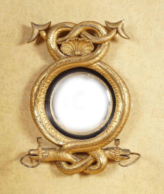 An Irish Regency carved giltwood convex mirror in a serpent entwined frame at Sheppards. An Irish Regency carved giltwood convex mirror in a serpent entwined frame at Sheppards.