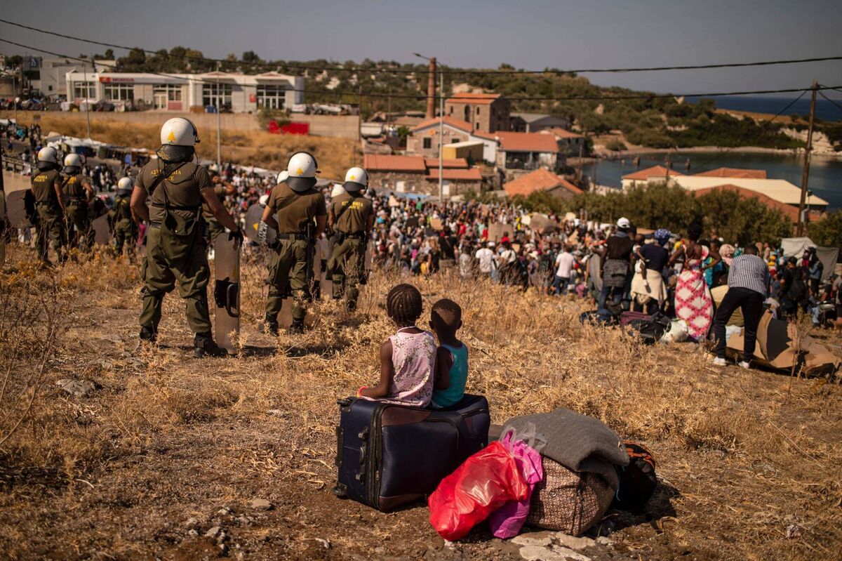 Two girls sit on a suitcase as they watch other refugees and migrants from the Moria refugee camp protesting on the Greek island of Lesbos, last September after a fire destroyed the camp. Picture: Angelos Tzortzinis/AFP/Getty