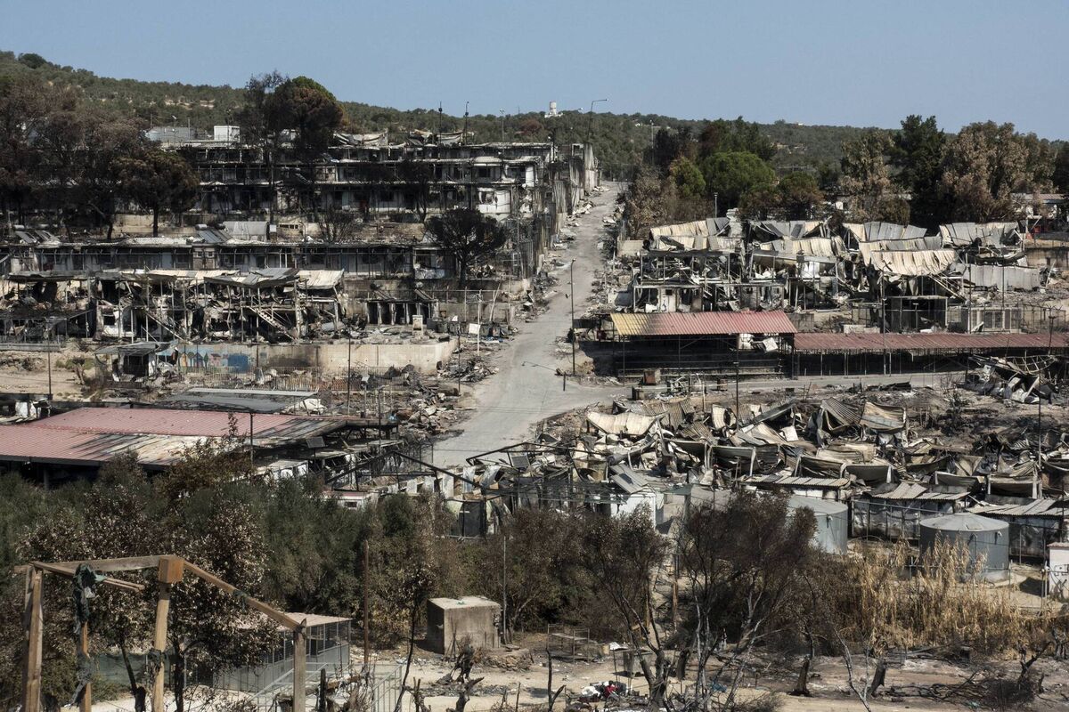 A group of refugees carry the belongings they salvaged from the Moria refugee camp after it became unusable following fires that erupted on September 9 last year. Picture: Ayhan Mehmet/Anadolu/Getty