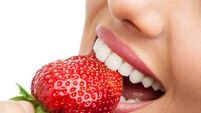 Extreme close up of teeth biting strawberry.