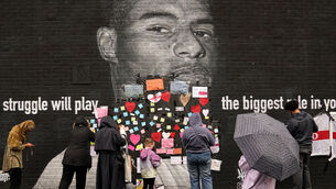 People place messages of support on top of bin liners that were taped over offensive wording on the mural of Manchester United striker and England player Marcus Rashford in Withington (Martin Rickett/PA)