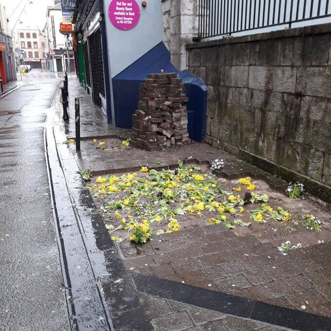 Dozens of paving stones had been removed at each of the locations and neatly stacked nearby with cut flowers and greenery left in their place to cover the spaces. Pictured are the missing bricks in the road between Patrick Street and Paul Street. Photo: Cork City Council.