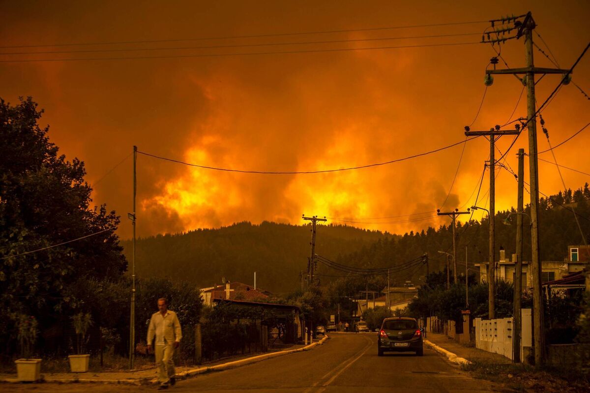 A local resident walks as a wildfire rages near the village of Gouves, on Euboea island, second largest Greek island. Picture: ANGELOS TZORTZINIS / AFP via Getty Images)