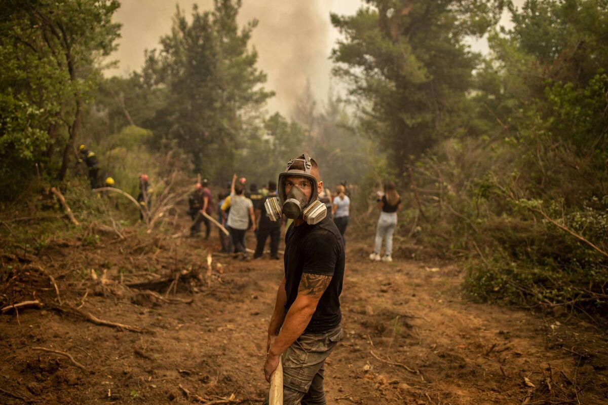 A volunteers helps firefighters to extinguish the burning blaze of a forest fire near in the village of Avgaria on Evia (Euboea) island, on Tuesday. Picture: Angelos Tzortzinis /AFP via Getty Images