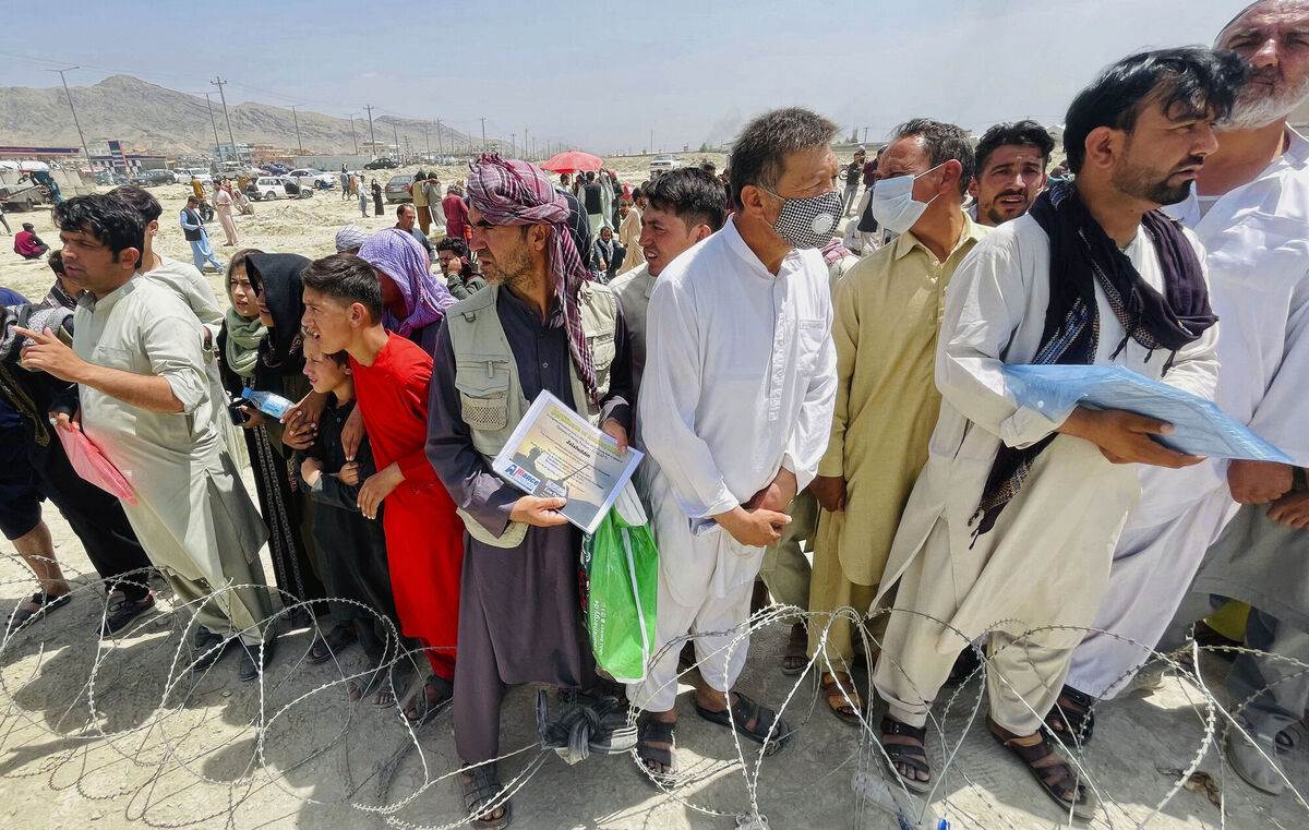 A man holds a certificate acknowledging his work for Americans as hundreds of people gather outside the international airport in Kabul, Afghanistan, Tuesday. Picture: AP 