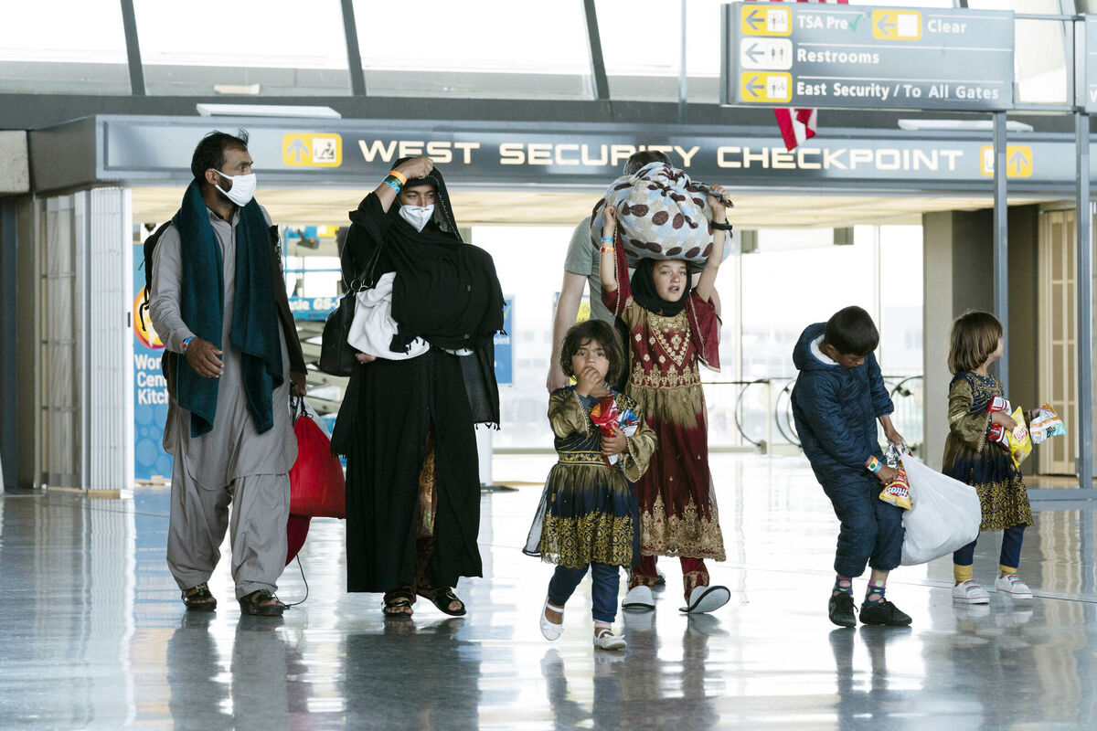 Families evacuated from Kabul, Afghanistan, walk through the terminal before boarding a bus after they arrived at Washington Dulles International Airport