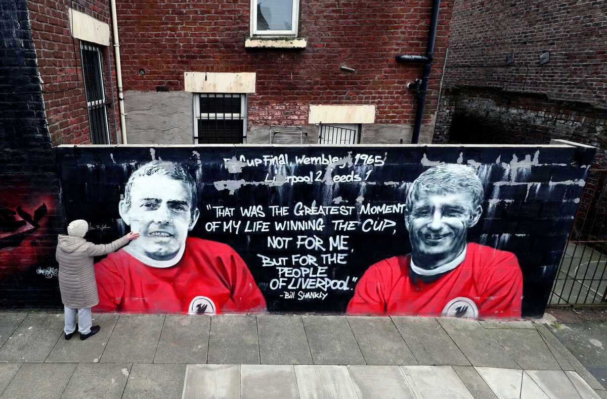 A woman touches the Ian St John mural where he is pictured alongside his strike partner and Roger Hunt in a mural created by Murwalls. Picture: Peter Byrne/PA A woman touches the Ian St John mural where he is pictured alongside his strike partner and Roger Hunt in a mural created by Murwalls. Picture: Peter Byrne/PA