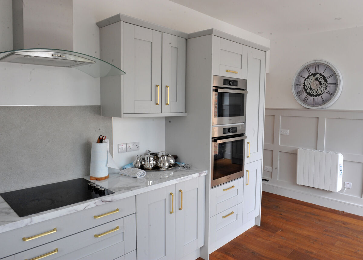 A long room formed from the original footprint, a new extension sitting on a former lean-to, the kitchen has a nicely detailed kitchen embracing Rena’s indoor dining area, and matches the grey of the paneling throughout the main living spaces. Declan Hennessy, a manager for Cash &amp; Carry Kitchens is a member of the Ahern family and supplied the kitchen, making the most of that quay side sash widow piercing the monumental walls of Allins Quay.
