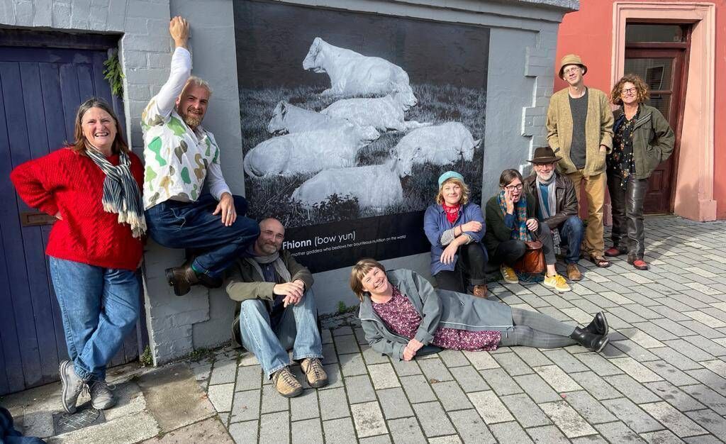 Toma McCullim, Will Bock, Tomasz Madajczak, Sharondipity, Millie Egan, Muireann Brady, Tich Breathnach, Manchán Magan and Carmel Winters, pictured in front of an image by Tich Breathnach for Bó Fhionn - a mother goddess who bestows her bounty on the world.