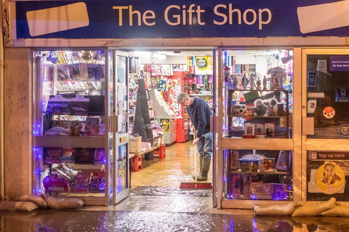 A man sweeps floodwater from his shop in Bantry. Photo: Andy Gibson/PA