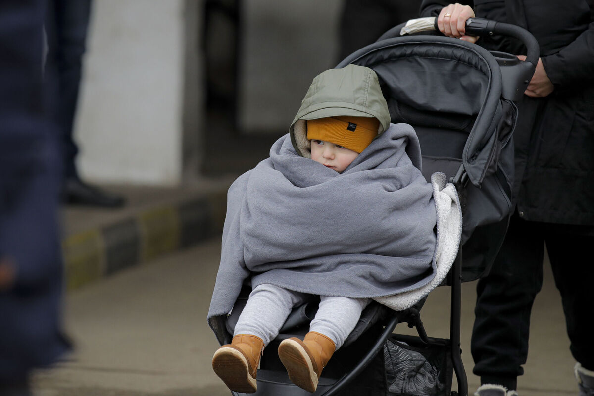 Wrapped in a blanket against the bitter cold, one of the thousands of children arriving in Romania is wheeled to safety by her mother after fleeing the conflict in neighbouring Ukraine. Picture: Andreea Alexandru/AP Wrapped in a blanket against the bitter cold, one of the thousands of children arriving in Romania is wheeled to safety by her mother after fleeing the conflict in neighbouring Ukraine. Picture: Andreea Alexandru/AP