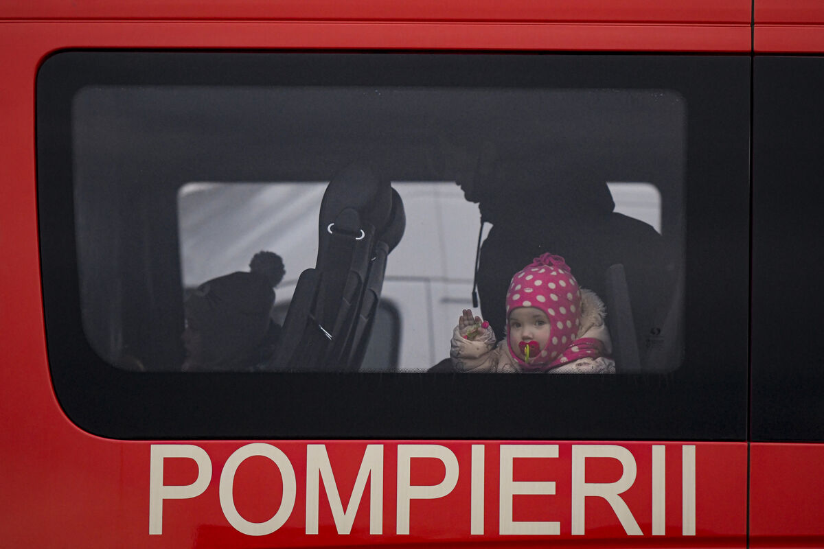 A toddler waves from a bus provided by the Pompierii (the Romanian term for fire brigade) in Siret, Romania, as tens of thousands of families flee the invasion of Ukraine. Picture: Andreea Alexandru/AP