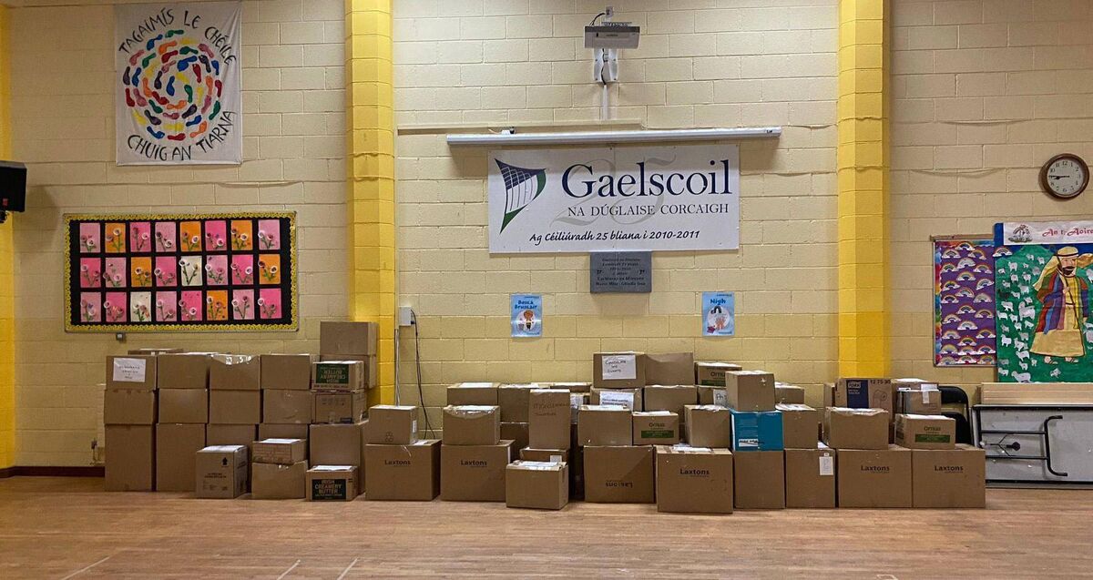 A clock, banners, children's artwork: Gaelscoil na Dúglaise's halla is like halls in schools all around the world. The difference is the boxes of aid ready to go to the Polish-Ukrainian border. Picture: Twitter/@gaelscoilnadug1
