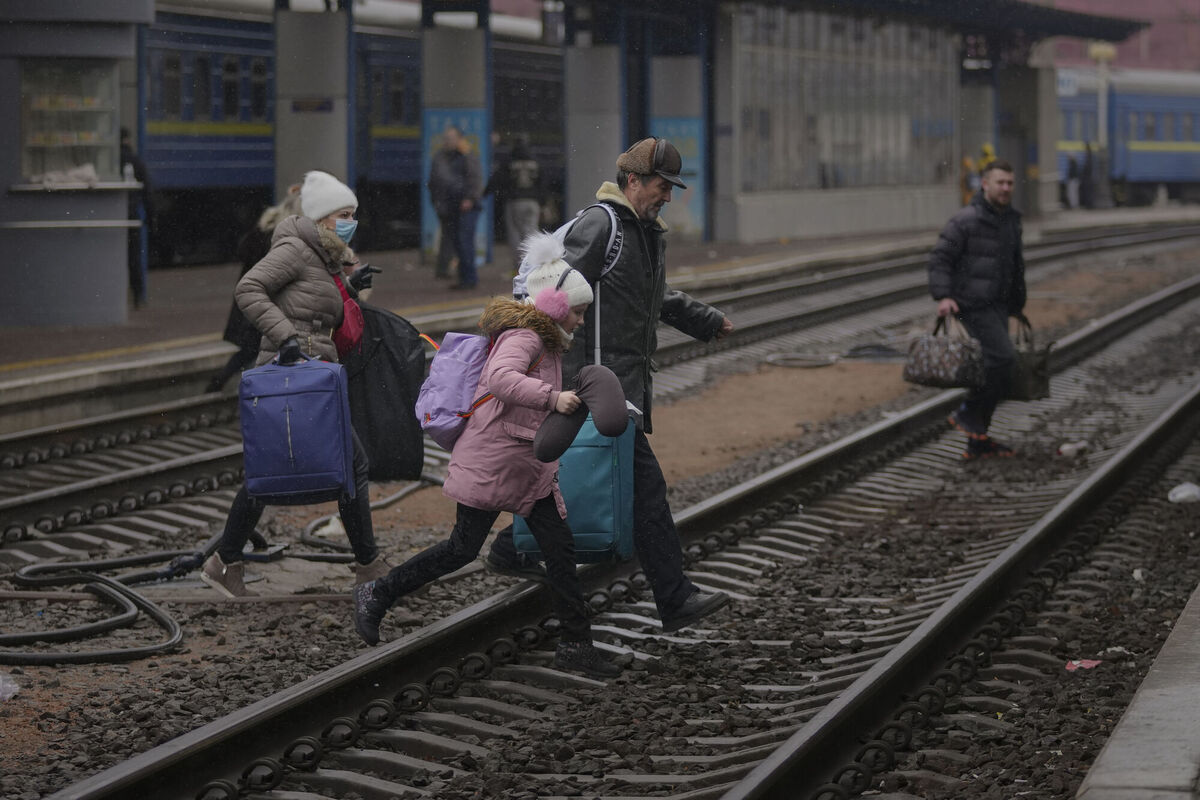 A family runs over the tracks trying to board a Lviv bound train, in Kyiv, Ukraine. Picture: AP Photo/Vadim Ghirda
