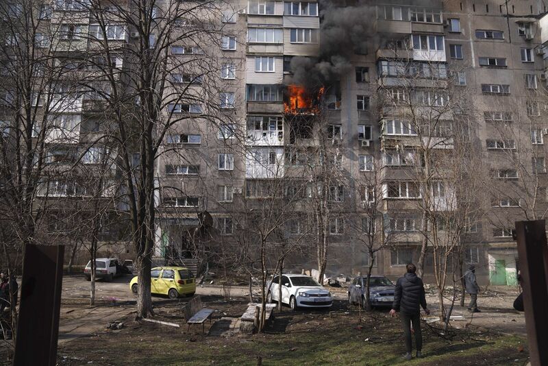 People look at a burning apartment building in a yard after shelling in Mariupol, Ukraine. Picture: AP Photo/Evgeniy Maloletka