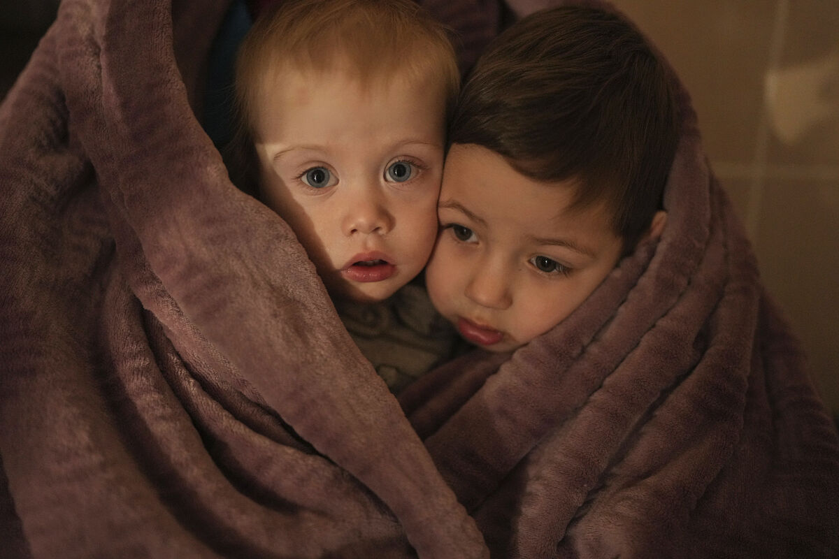 The children of medical workers warm themselves in a blanket as they wait for their relatives in a hospital in Mariupol, Ukraine, March 4, 2022. (AP Photo/Evgeniy Maloletka)