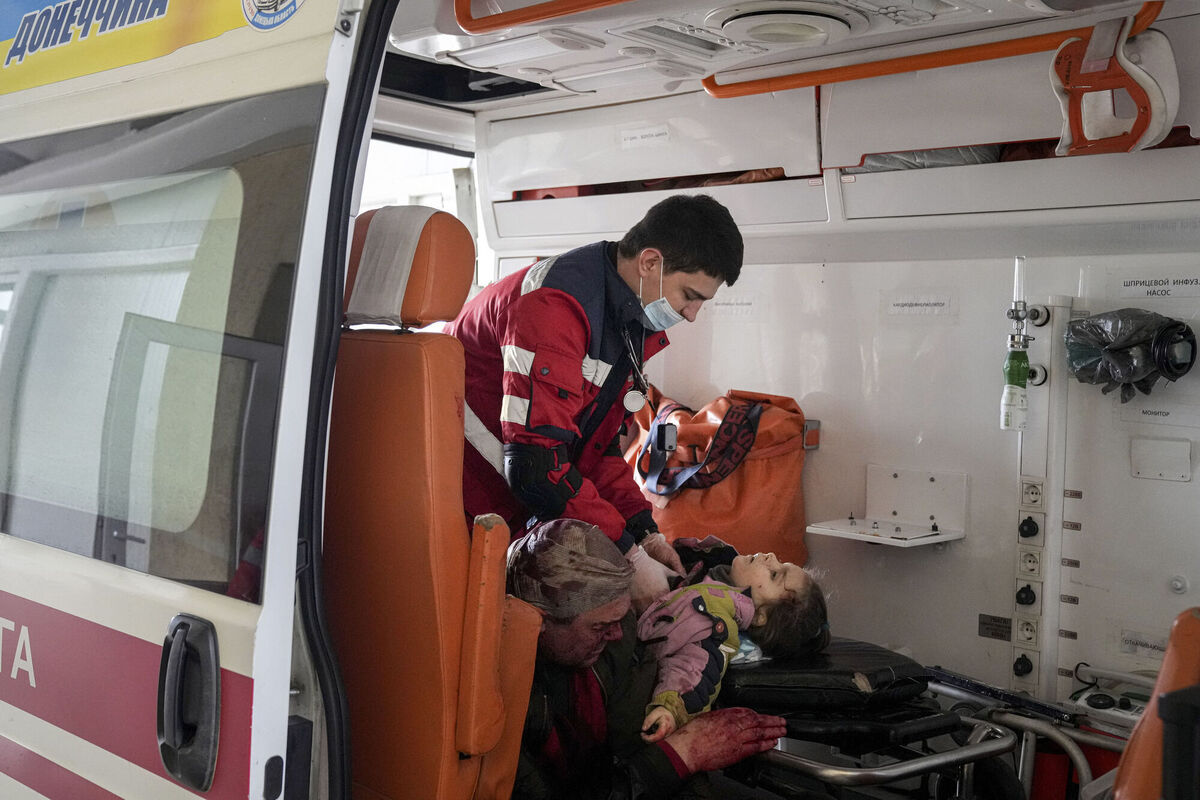 Oleksandr Konovalov, an ambulance paramedic, performs CPR on a girl injured by shelling in a residential area as her dad sits, left, after arriving at the city hospital of Mariupol, eastern Ukraine, Sunday, Feb. 27, 2022. The girl did not survive. (AP Photo/Evgeniy Maloletka)