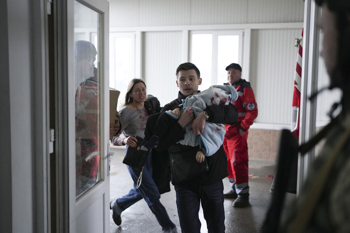 Marina Yatsko, left, runs behind her boyfriend Fedor carrying her 18 month-old son Kirill who was killed in shelling, as they arrive at a hospital in Mariupol, Ukraine, Friday, March 4, 2022. (AP Photo/Evgeniy Maloletka)