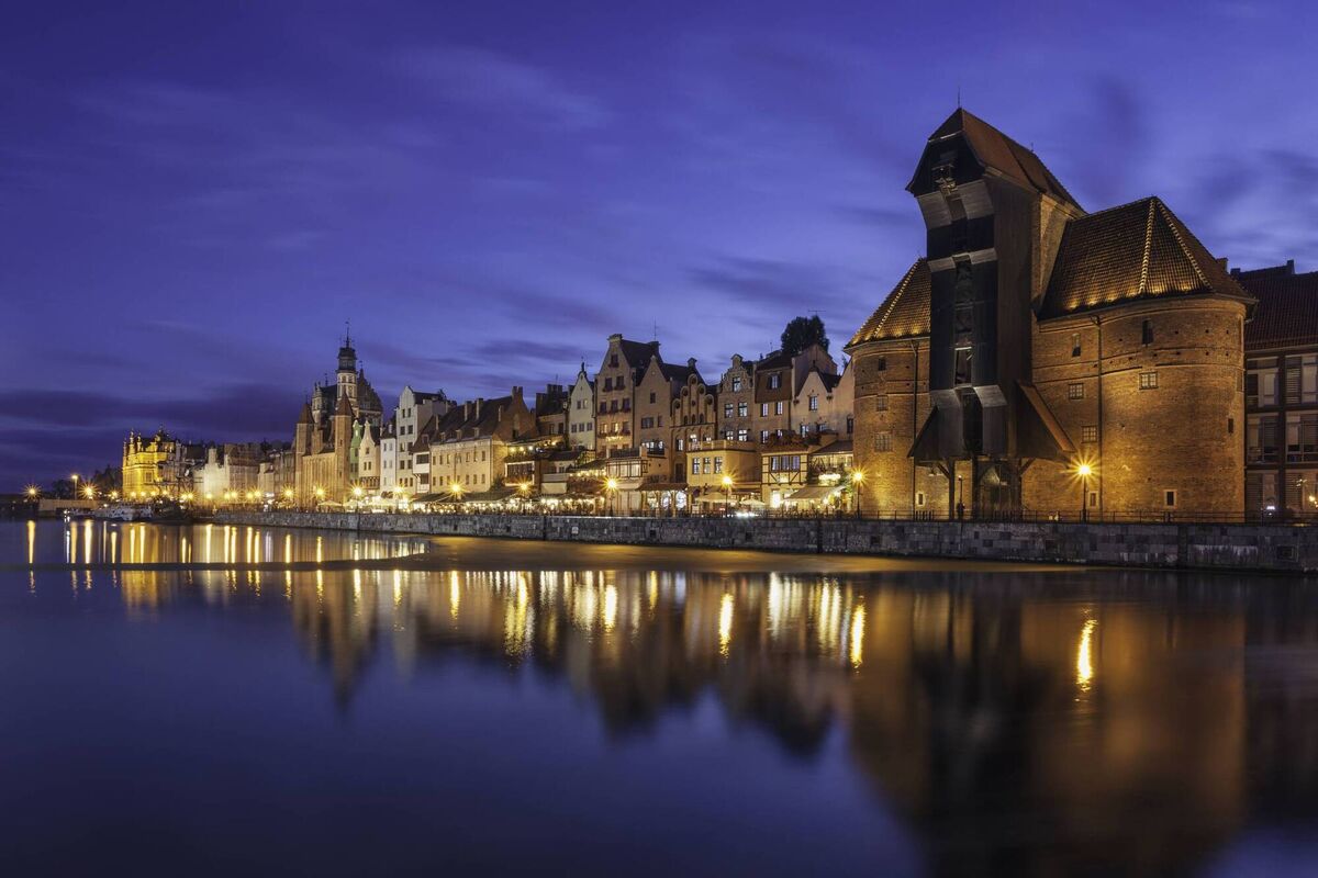 The old town of Gdansk by the Motlawa river in the evening. On the right is a historical wooden crane, a landmark in the city.