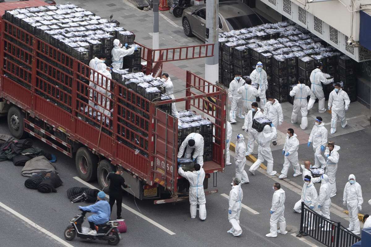 Workers in PPE unload groceries from a truck before distributing them to local residents under the COVID-19 lockdown in Shanghai, China