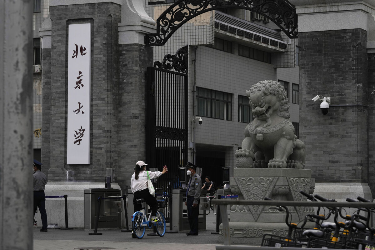 A woman shows a security guard proof for entry at an entrance to the main campus of Peking University in Beijing.  Picture: Ng Han Guan