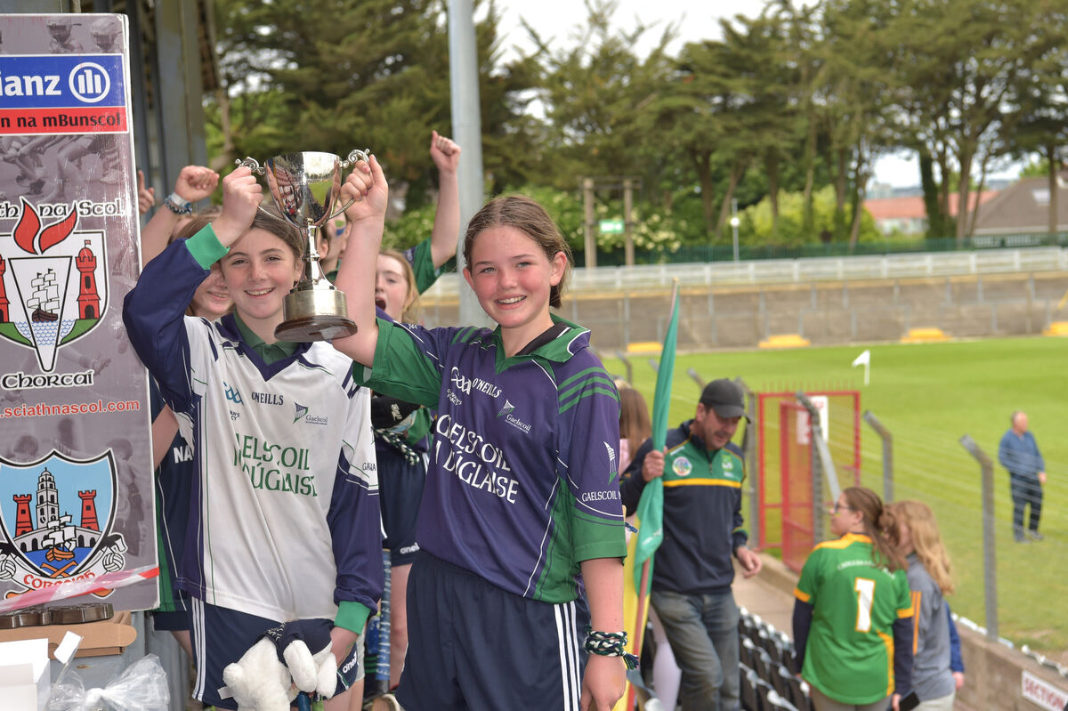  Maggie Nic Seoin and Frida Ni Mhuirí captain of Gaelscoil na Dúglaise team receiving the cup from Sarah Clinch after their victory over Castlelyons in their C3 final