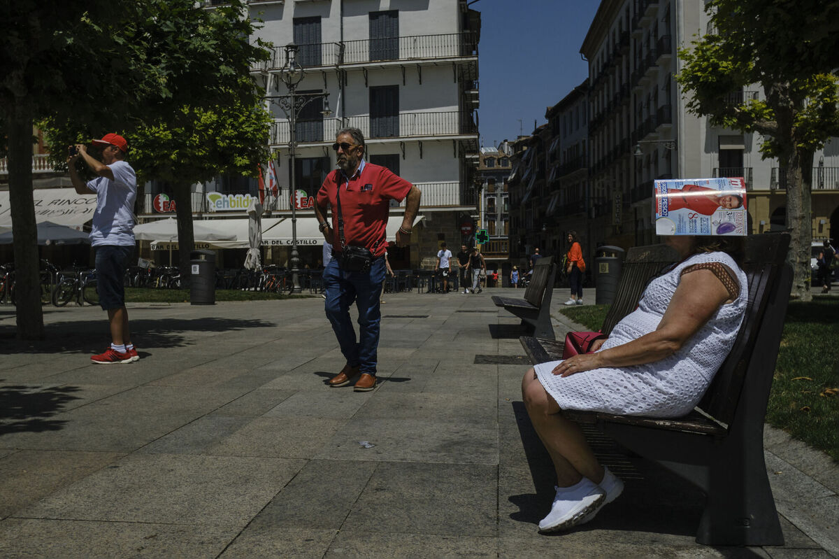 A woman protects her head under a magazine at Plaza del Castillo square in Pamplona, northern Spain. Picture: AP Photo/Alvaro Barrientos