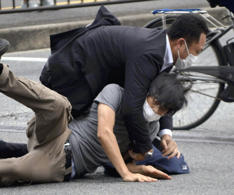 Tetsuya Yamagami, bottom, is detained near the site of gunshots in Nara Prefecture, western Japan. Picture: Katsuhiko Hirano/The Yomiuri Shimbun via AP